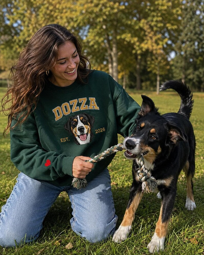 Woman wearing green Dozza portrait sweatshirt beside her dog