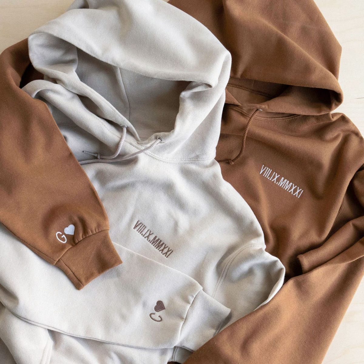 Brown and pale gray Roman numeral hoodies with embroidered initials