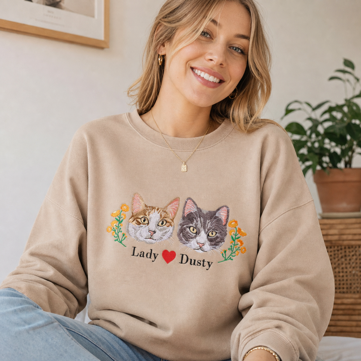 Woman wearing a beige Lady and Dusty cat portrait sweatshirt with orange floral details