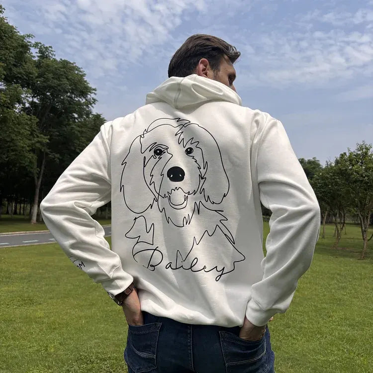 Male model wearing cream Bailey dog line art hoodie in a park