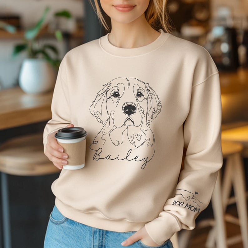 Woman in cream Bailey pet sweatshirt holding a coffee cup