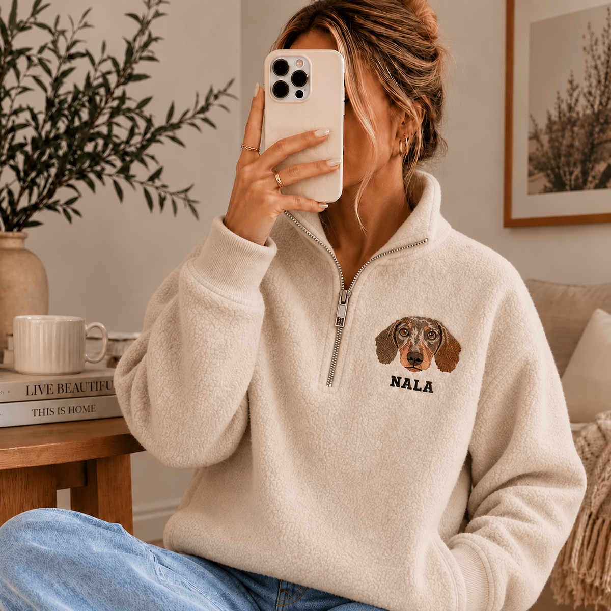 Model wearing cream fleece quarter zip with NALA dog portrait embroidery