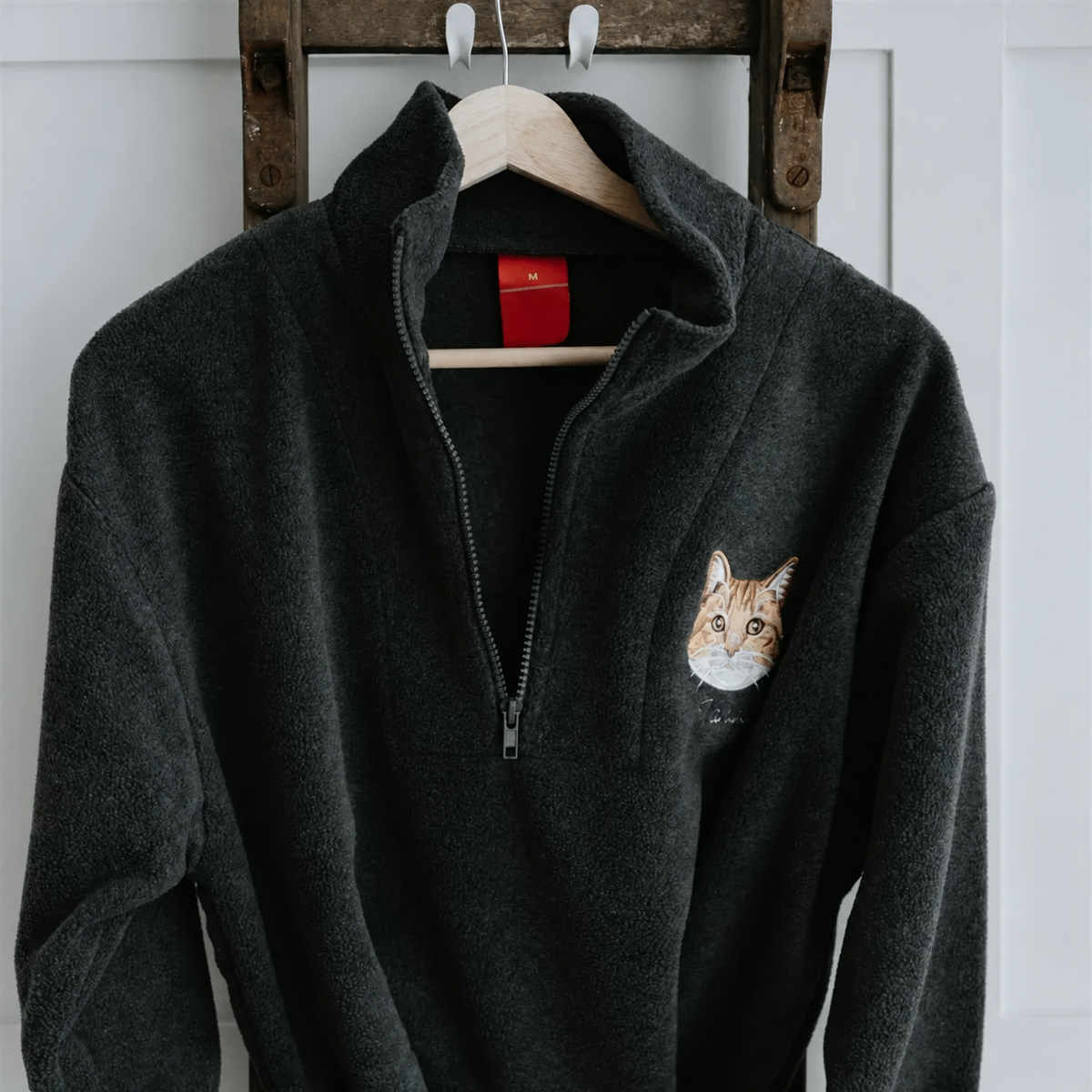 Black fleece quarter zip hanging with sleeve embroidery detail