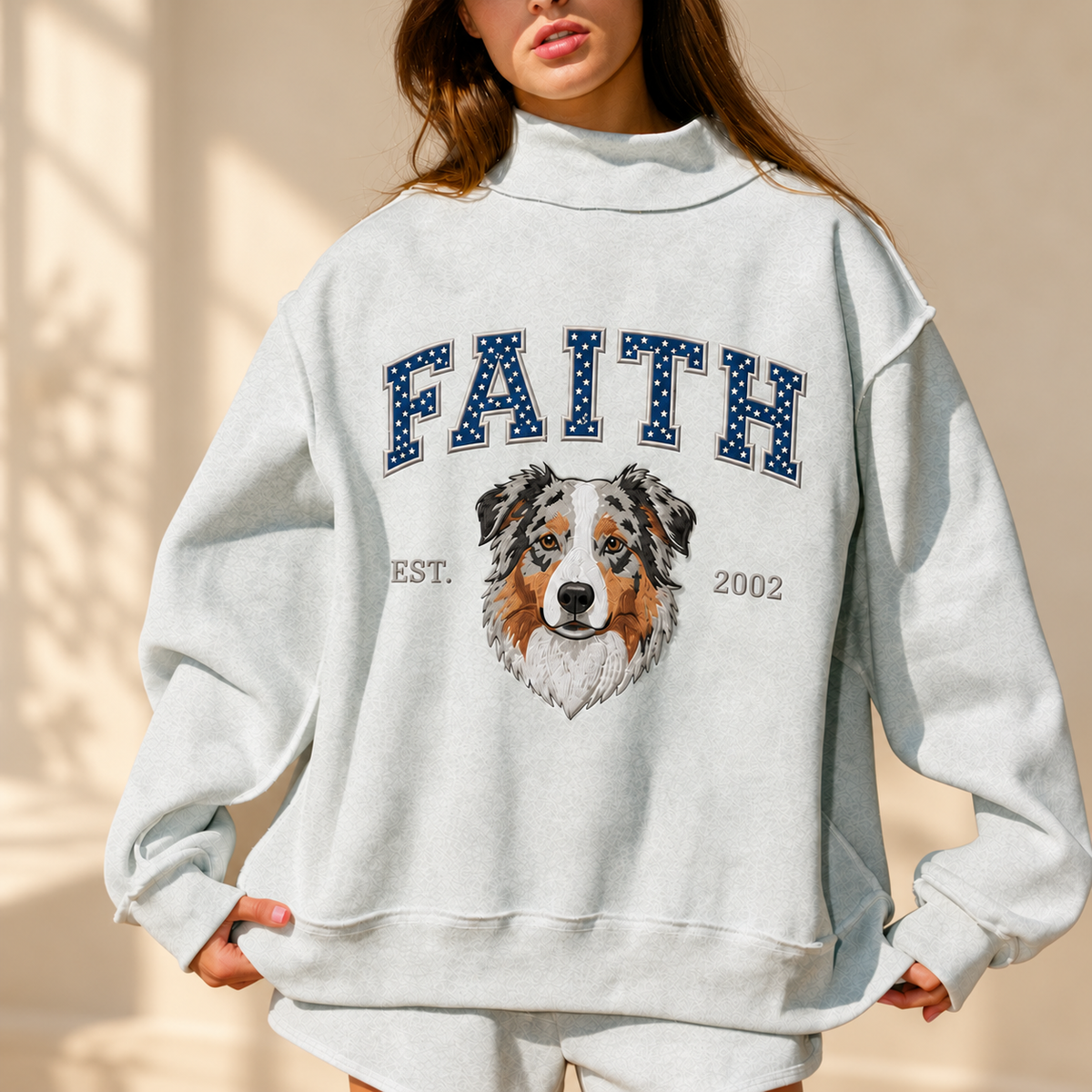 Woman in a heather gray mockneck sweatshirt with FAITH in navy varsity letters and an embroidered Australian shepherd, EST 2002