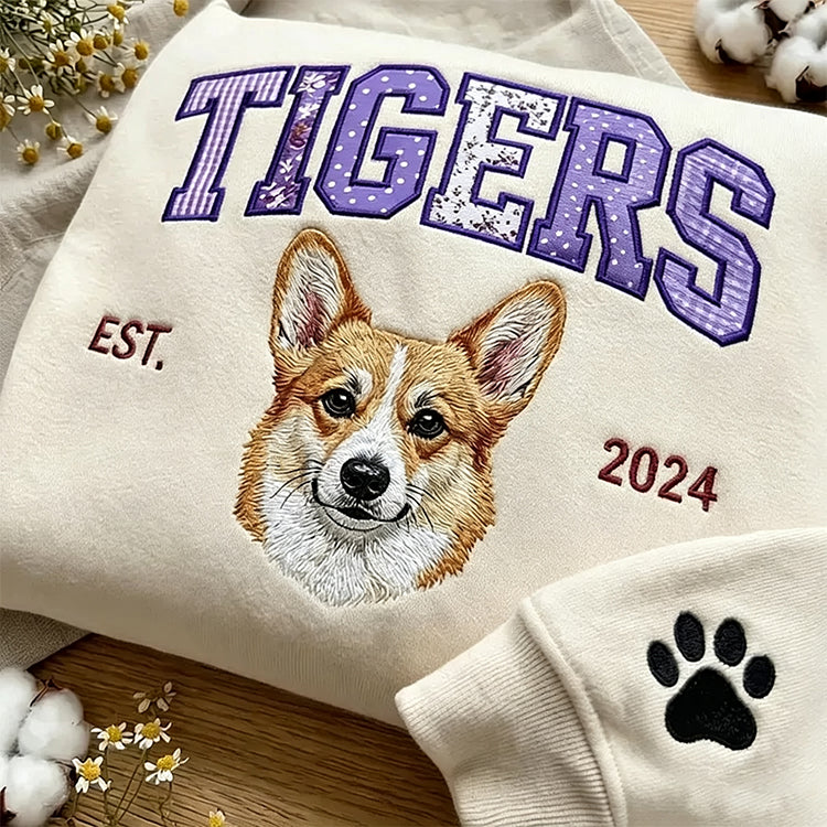 Cream sweatshirt with TIGERS in purple patchwork letters above an embroidered corgi, paw on the cuff