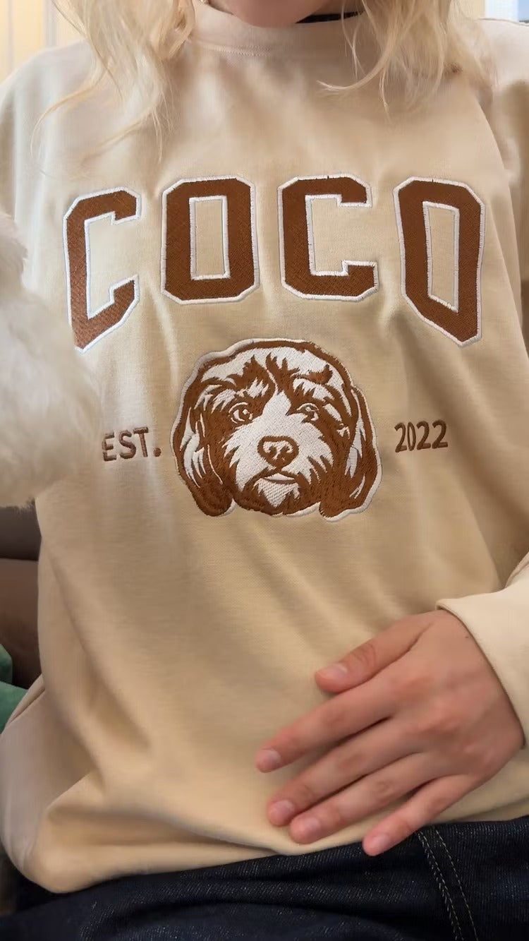 Woman wearing a cream sweatshirt with COCO in brown letters and a doodle outline