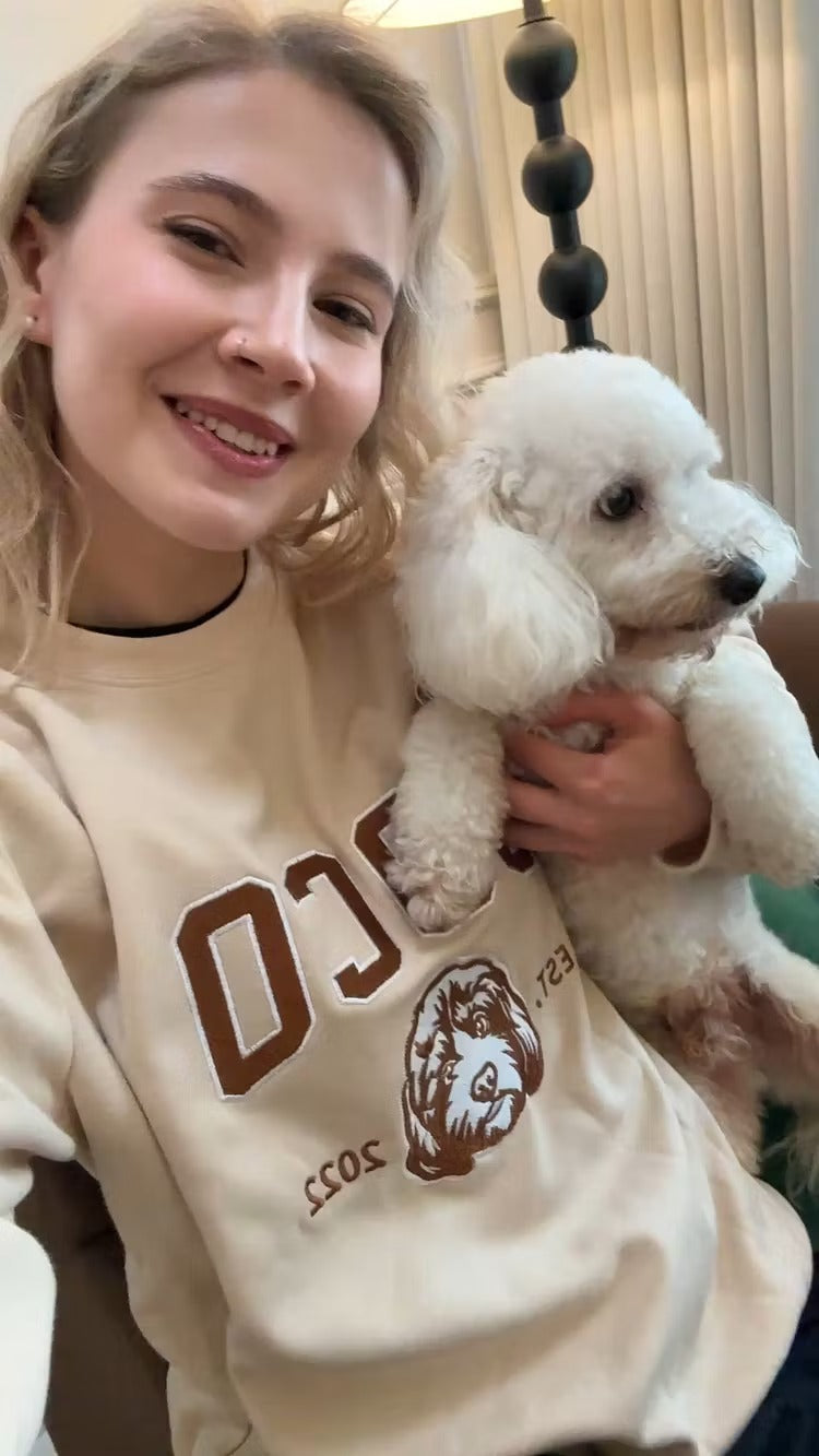 Woman holding a white poodle in a cream COCO pet outline sweatshirt