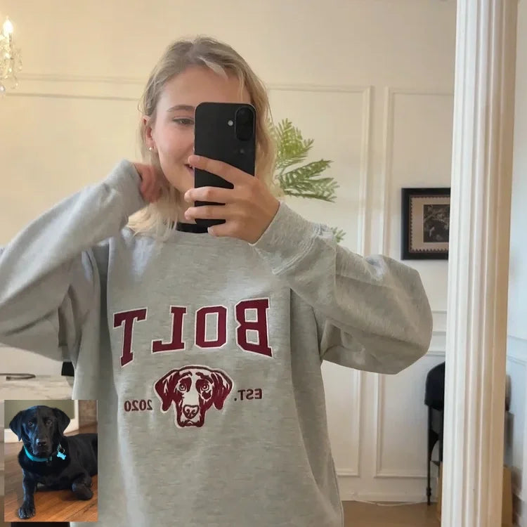 Mirror selfie in a gray BOLT sweatshirt with a black Labrador in the background